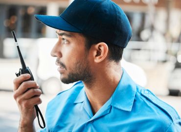 Security guard, safety officer or man on walkie talkie on a street for protection, patrol or watch.